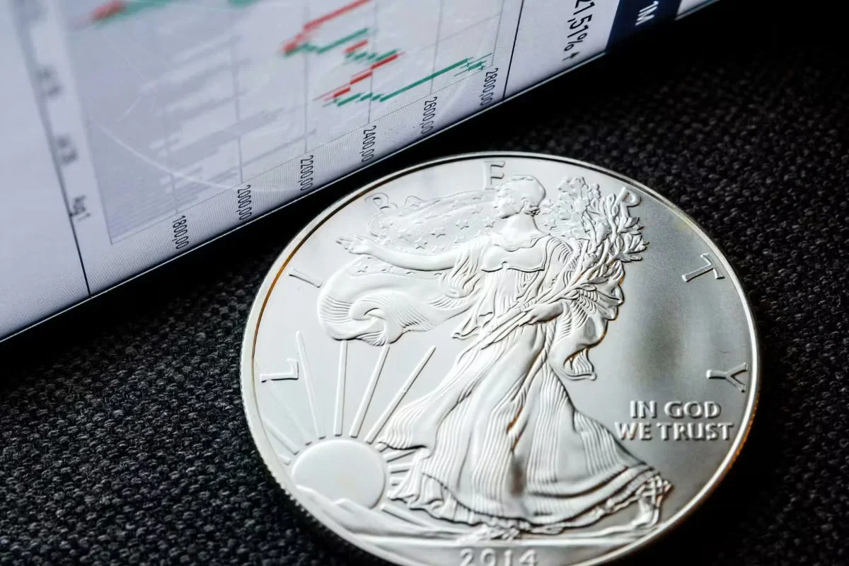 1767108952617_silver coin next to a financial chart on a screen